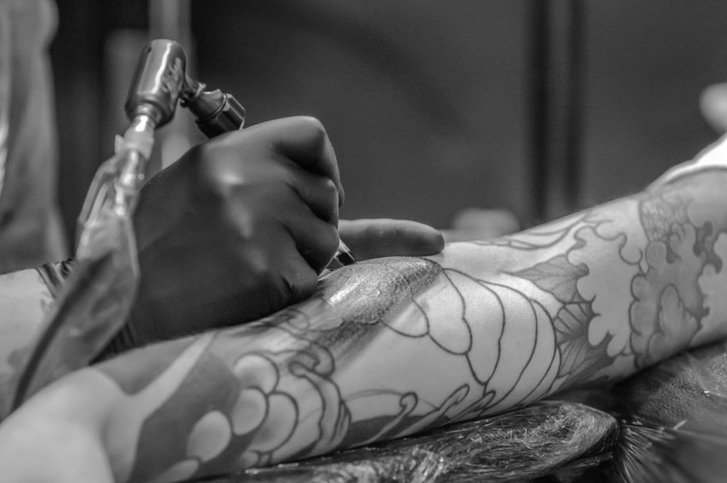 A closeup of a person applying a tattoo to another person's arm