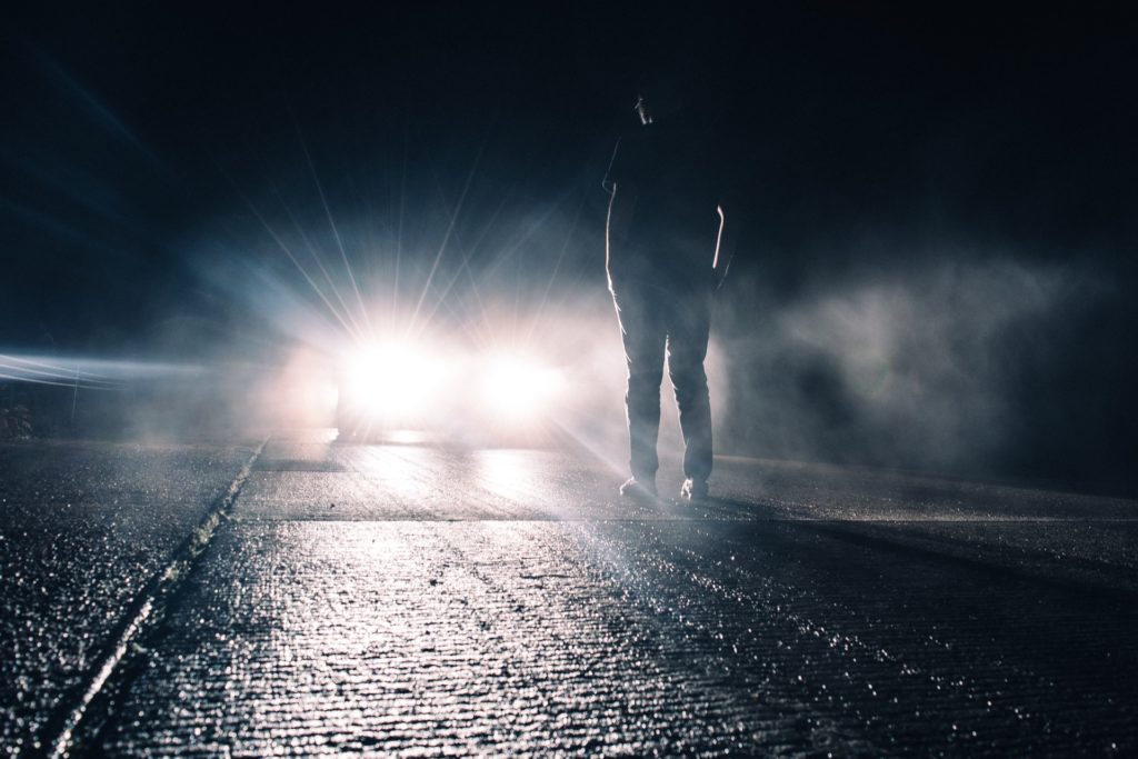 man standing in front of car with headlights