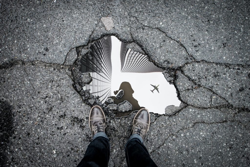 person standing over a pothole