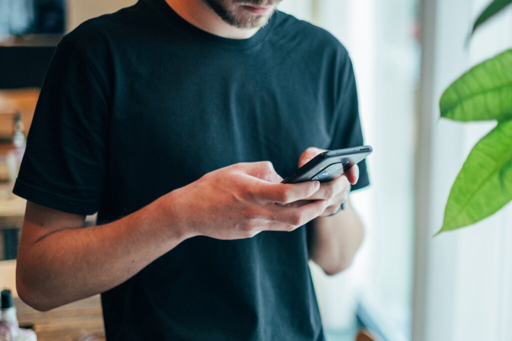 man in black crew neck top using cell phone